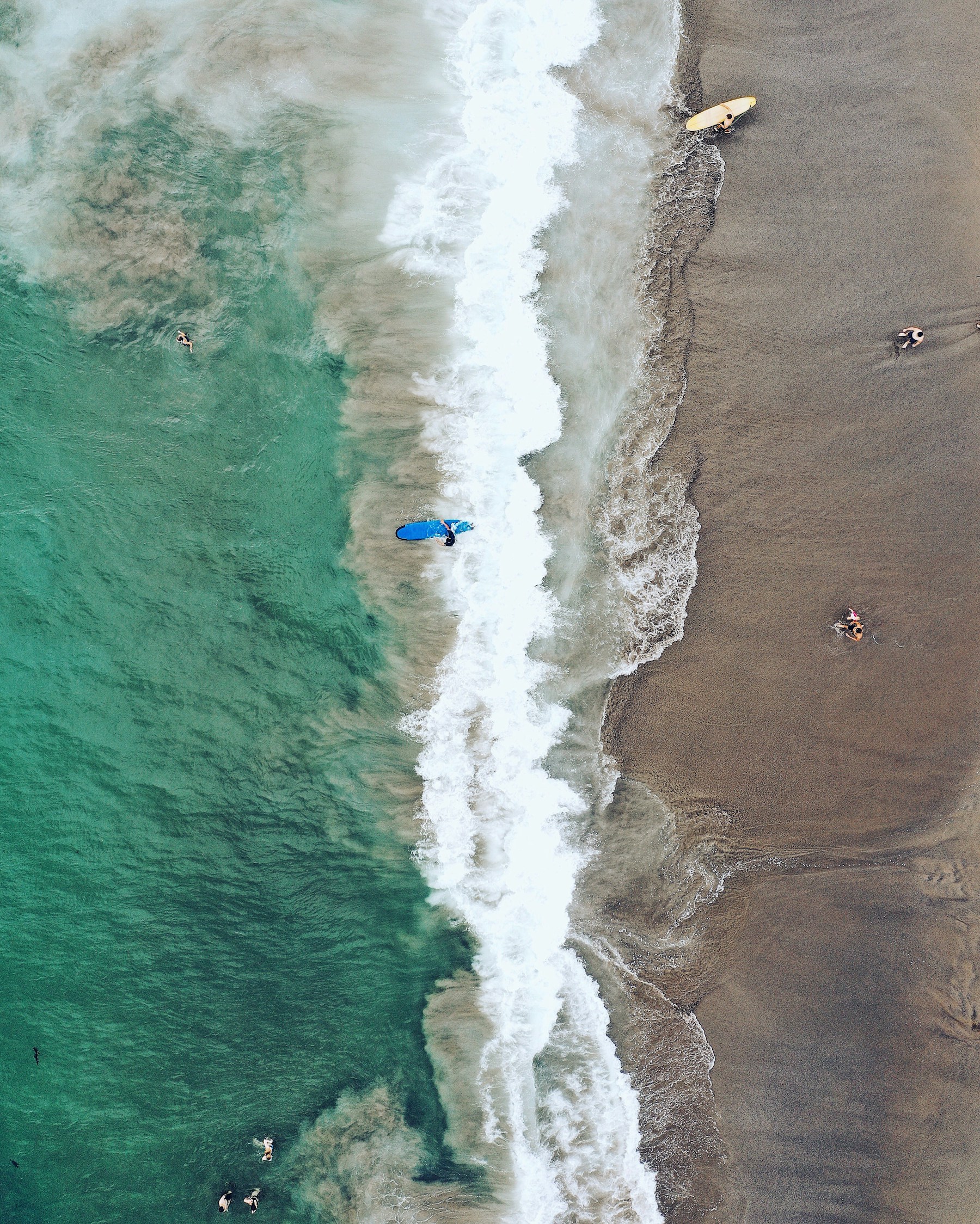 Surfers in the sunlit ocean off the Bali coast